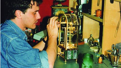 François-Paul Journe working on a remontoir-equipped Sympathique clock in his Paris workshop, between his early pocket watches and first tourbillon wristwatch.