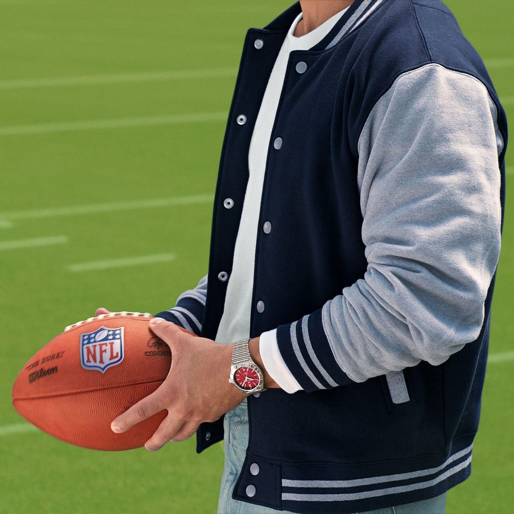 Man holds NFL Football with Breitling watch on his wrist. 