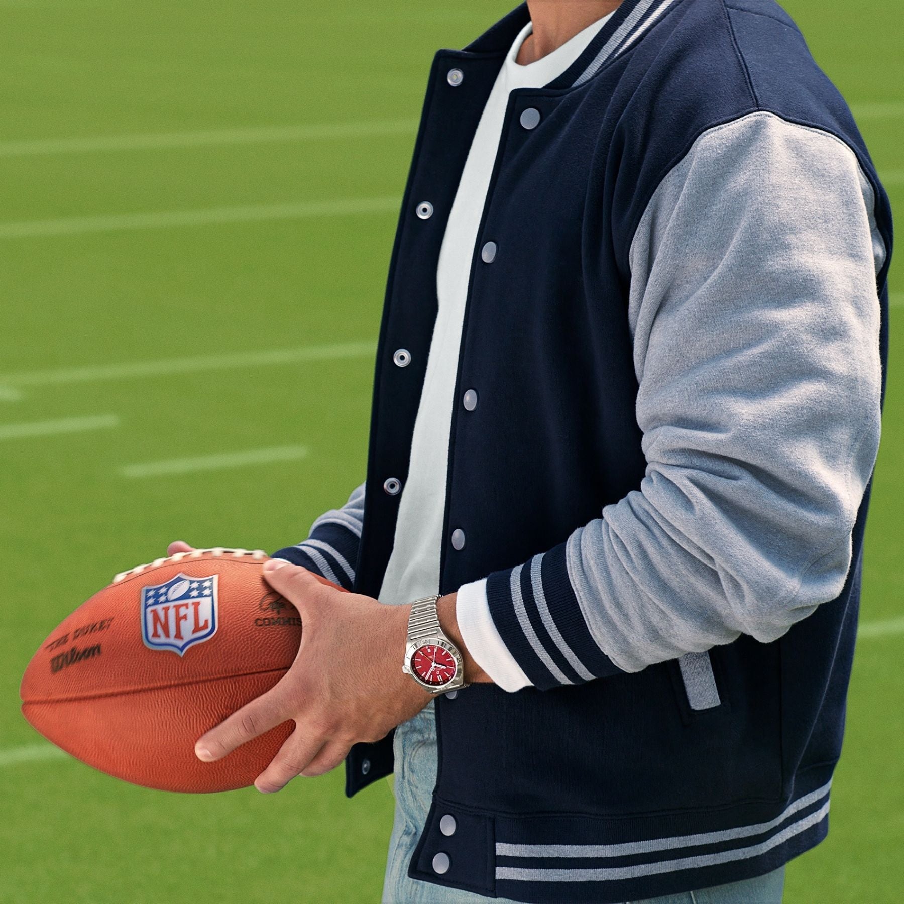 Man holds NFL Football with Breitling watch on his wrist.
